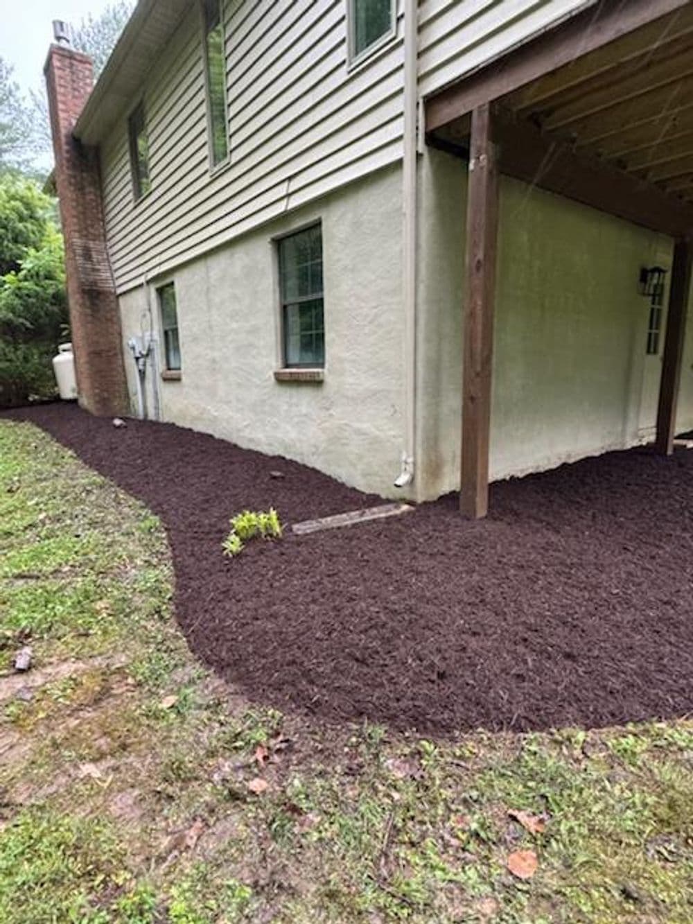 Freshly mulched garden bed beside a house, enhancing outdoor aesthetics and landscaping.