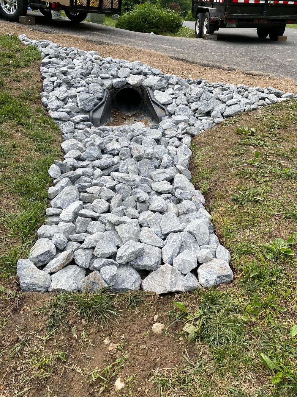 Rock drainage system directing water flow from a culvert into the grass area.